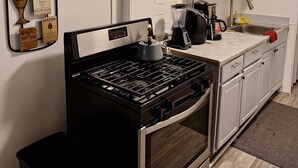 A modern kitchen with white cabinets, a stainless steel stove, a microwave, and a coffee maker. - DOWNTOWN AT CUTE AND COZY  (Atlanta)