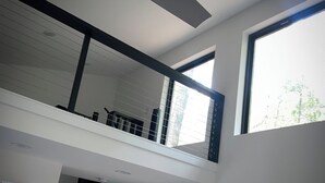 Un intérieur moderne au design de type « loft », comprenant un escalier, de grandes fenêtres et un ventilateur de plafond.