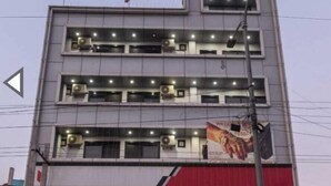 Un immeuble à plusieurs étages doté d’une façade plate, de plusieurs unités de climatisation et d’une grande publicité sur le niveau inférieur.