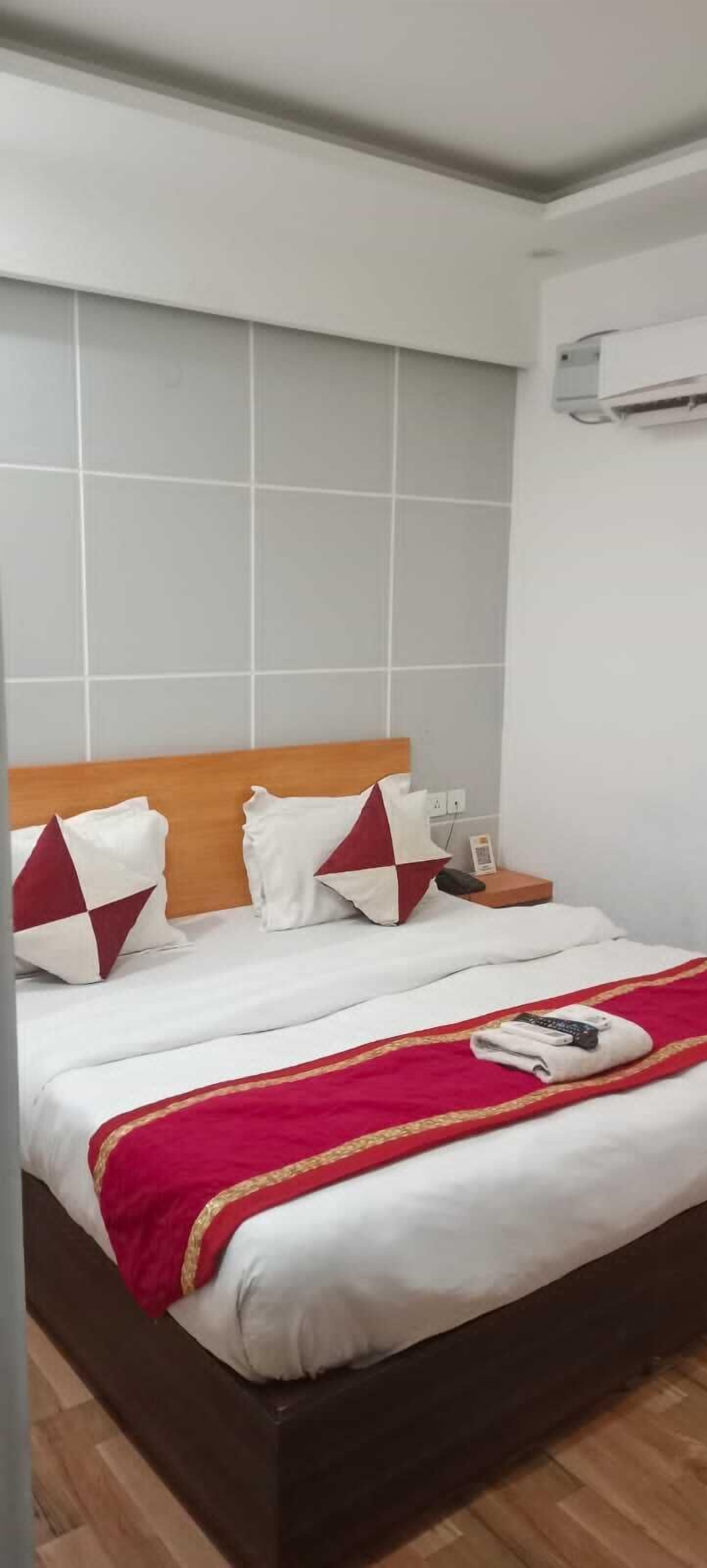 A hotel room with a wooden headboard, white bedding, and a red throw blanket.