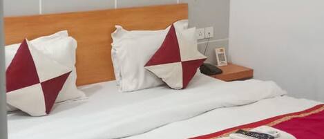 A hotel room with a wooden headboard, white bedding, and a red throw blanket.