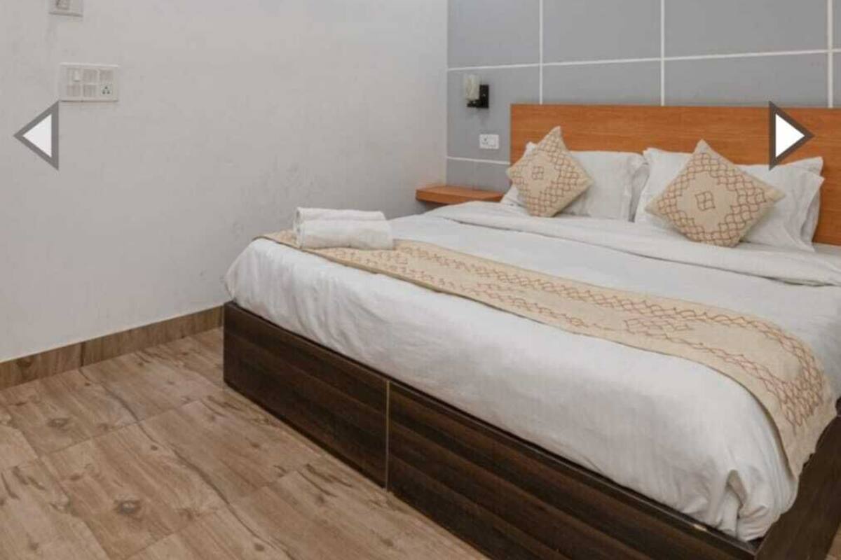 A modern bedroom with a large bed, a wooden headboard, and a tiled accent wall.