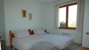 A bedroom with a double bed, two bedside tables, a window with curtains, and a small table with a chair. - Rural gite in the beautiful Lot et Garonne with air con. Heated swimming pool. (Coulx)