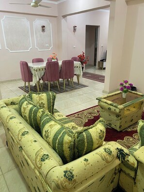 A living room with a sofa, a coffee table, and a dining table with chairs. - Cozy 1-bedroom apartment in awesome Luxor with AC, WiFi (Luxor)