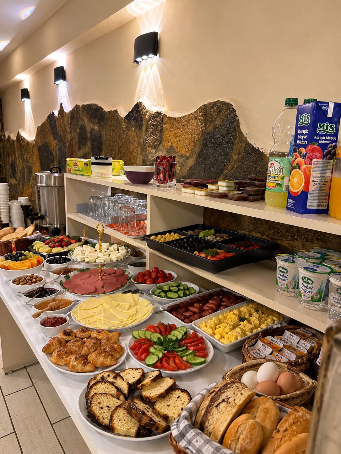 A buffet with various food items including meats, cheeses, fruits, and bread.