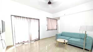 A modern living room with a light blue sofa, a round coffee table, and a floor lamp. - Aanand Riddhi (Pune)