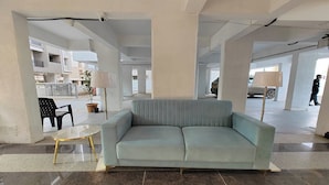 A modern interior with a light blue sofa, a glass table with gold legs, and a potted plant. - Aanand Riddhi (Pune)
