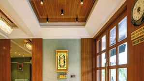 A reception area with a wooden ceiling, a framed picture on the wall, and a reception desk with a clock. - Hotel U Connect Near RTO Office, Udaipur (Udaipur)