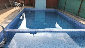 A rectangular swimming pool with a tiled edge and a metal ladder. - Saubhagya Villa (Mahabaleshwar)