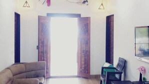 A spacious living room with a wooden ceiling, a sofa, a coffee table, and a TV on the wall. - Saubhagya Villa (Mahabaleshwar)