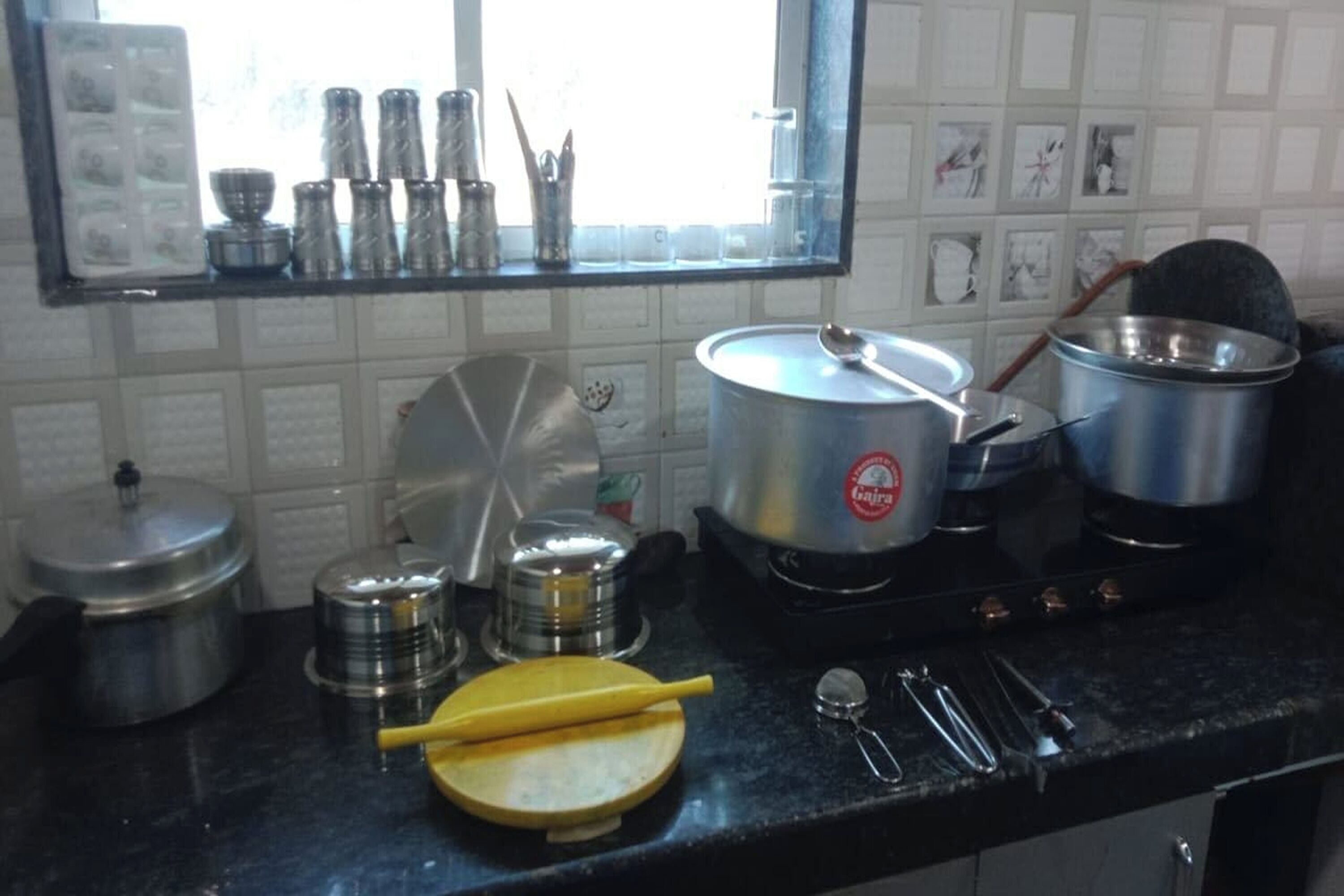 Uma cozinha com diversos utensílios de cozinha, panelas e uma janela com vista para o exterior.