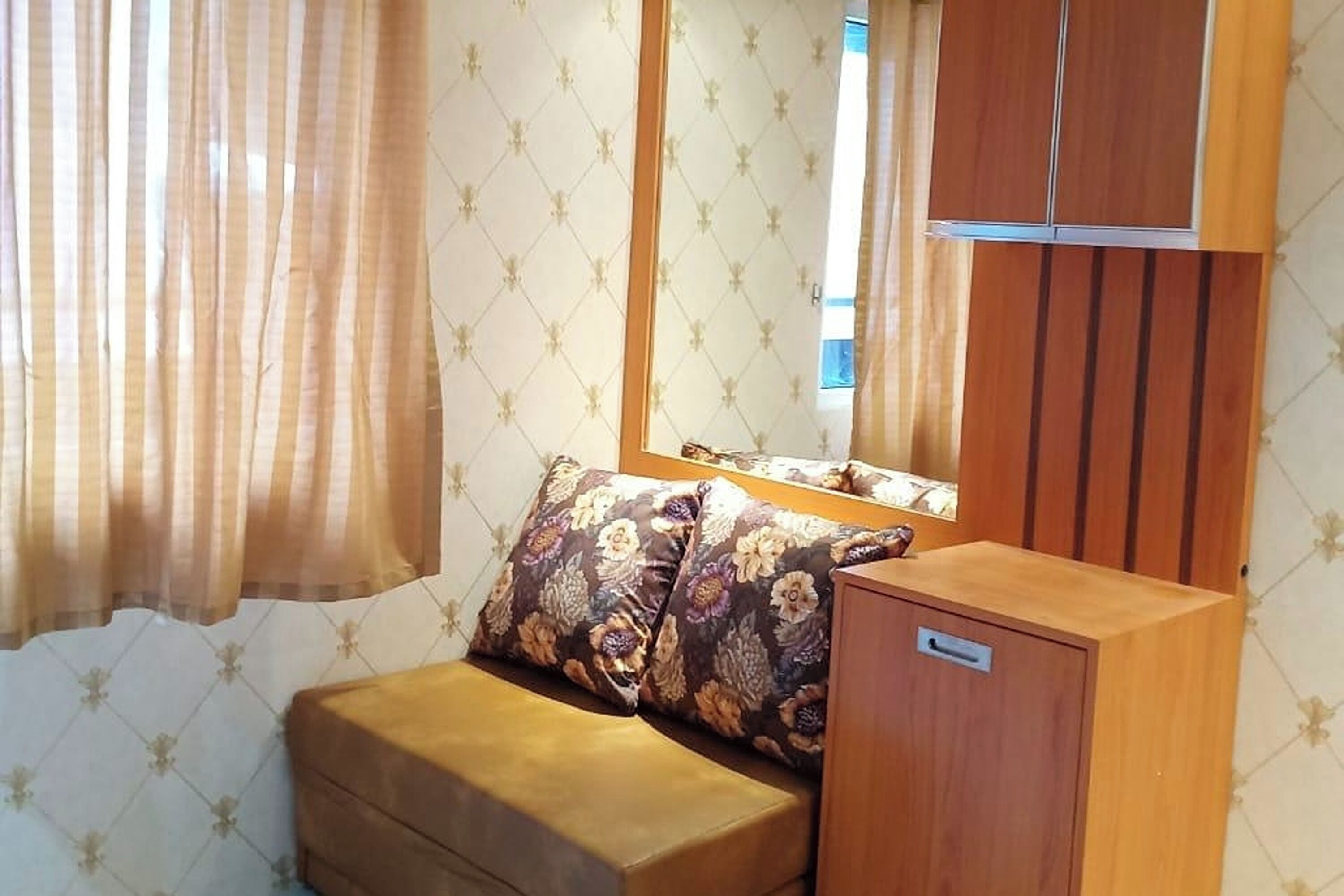 A compact room with a sofa, a small cabinet, and a mirror.