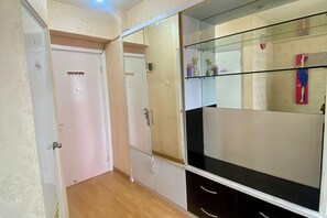 Ein Flur mit einer weißen Tür, einem beschrifteten Schrank mit schwarz-weißen Schubladen und einem Regal mit Flaschen.