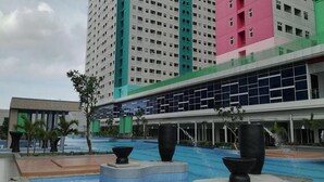 A hotel with a large pool area, multiple floors, and a modern architectural design. - Green Pramuka By Uchi Property (Jakarta)
