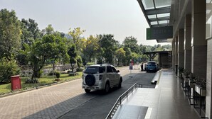 A parking area with a white SUV, a blue car, and a red mailbox. - Green Pramuka By Uchi Property (Jakarta)