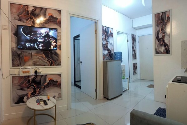 A modern kitchen with a flat-screen TV, marble wall art, and a refrigerator. - Green Pramuka By Uchi Property (Jakarta)