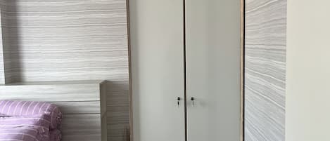 A bedroom with a bed, a wardrobe, and a wooden headboard.