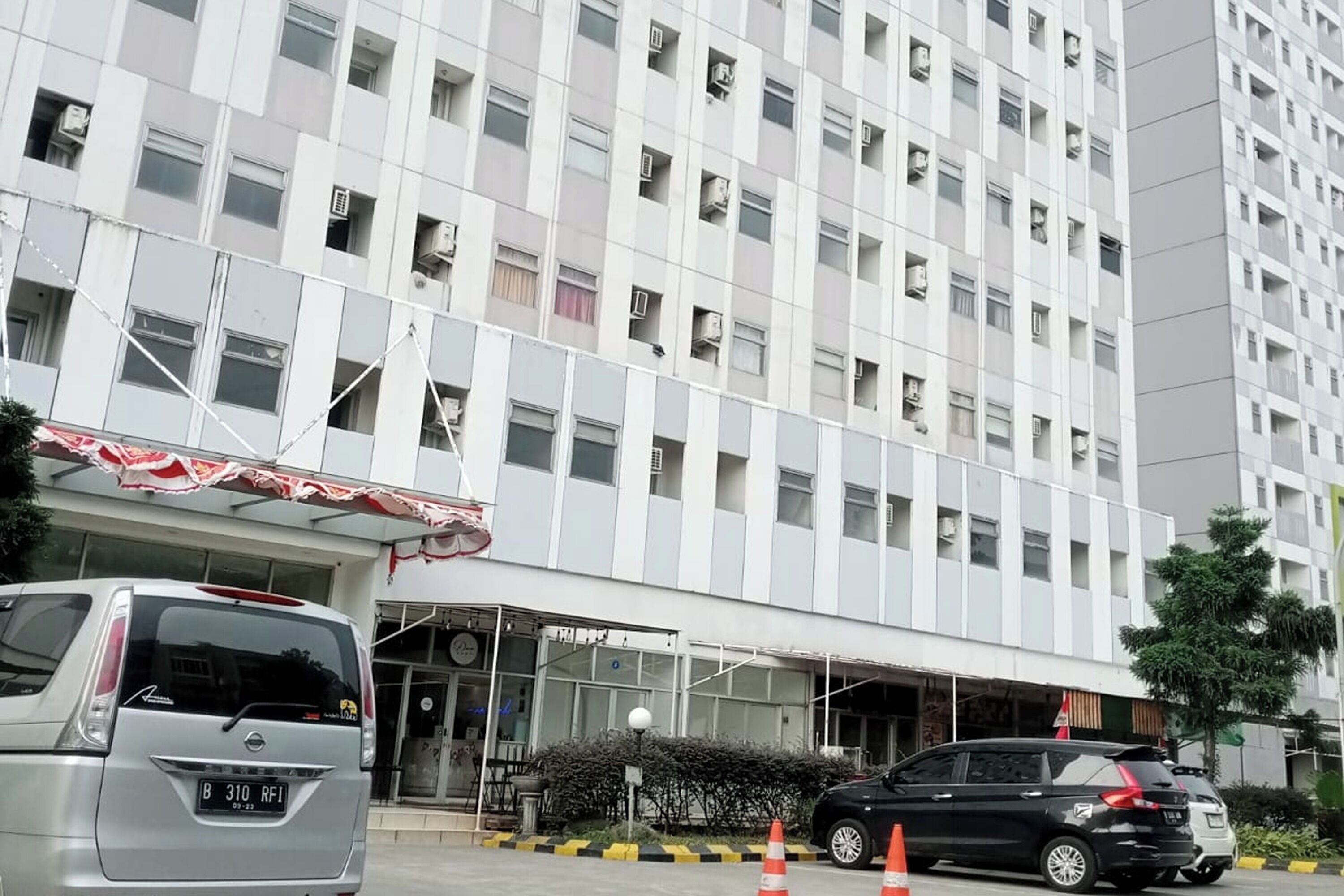 A modern building with a flat facade, multiple windows, and a covered entrance area.