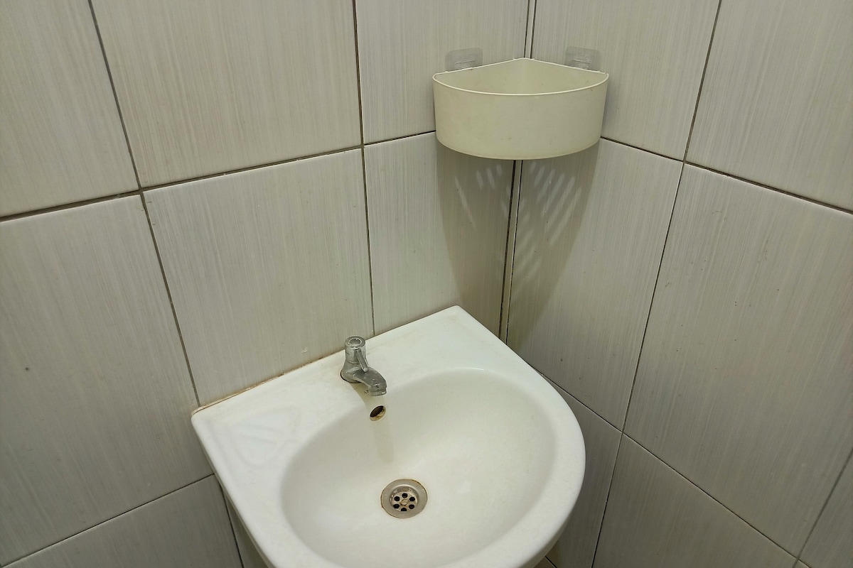 A bathroom with a white sink, a mirror, and a wall-mounted light fixture.