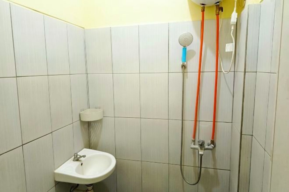 A bathroom with a sink, a shower with two hoses, and a toilet.