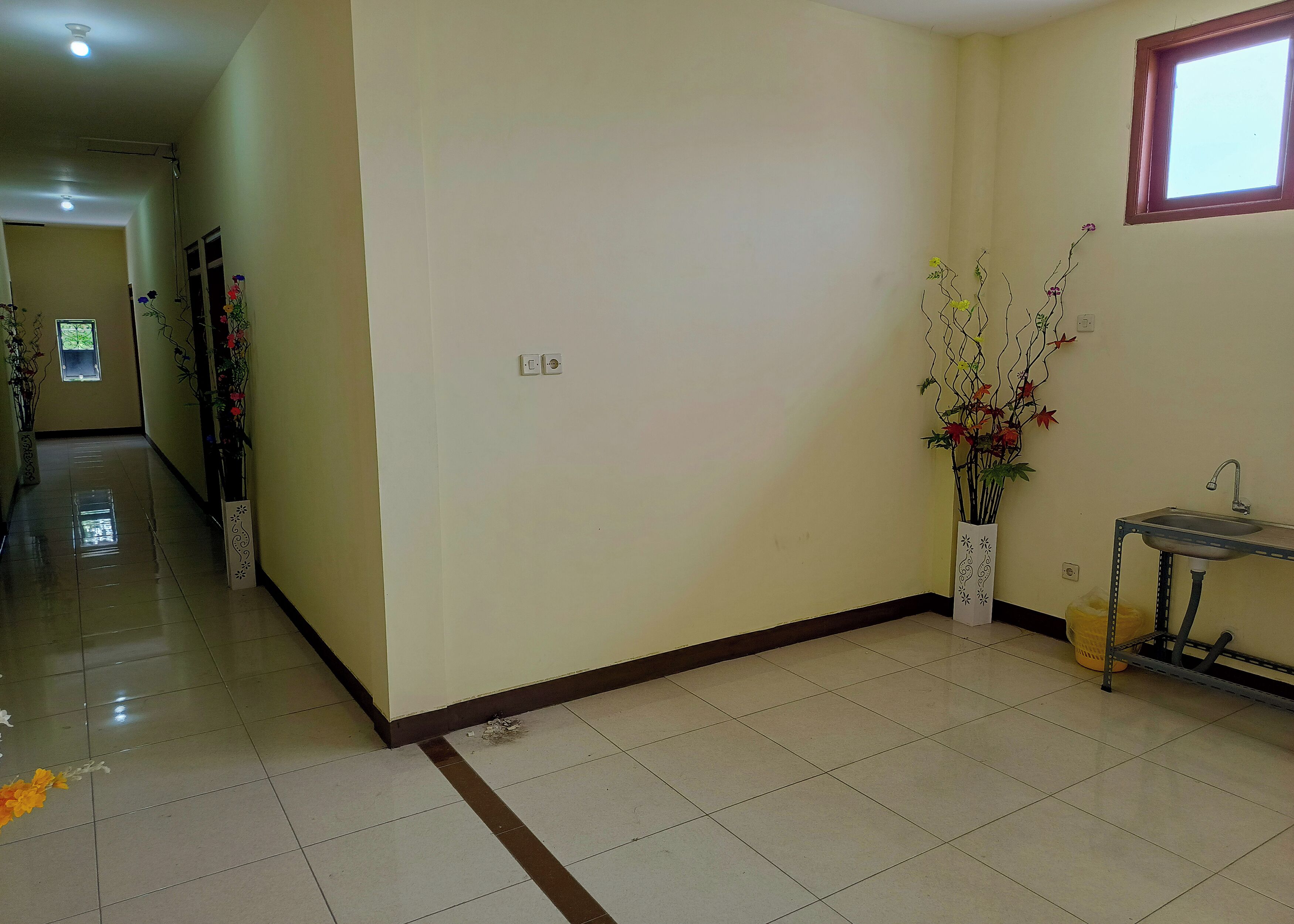 A hallway with a tiled floor, a door, and a window with a view.