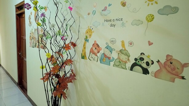 Ein Flur mit einer Wand voller Kinderzeichnungen und einer an der Wand befestigten Pflanze.