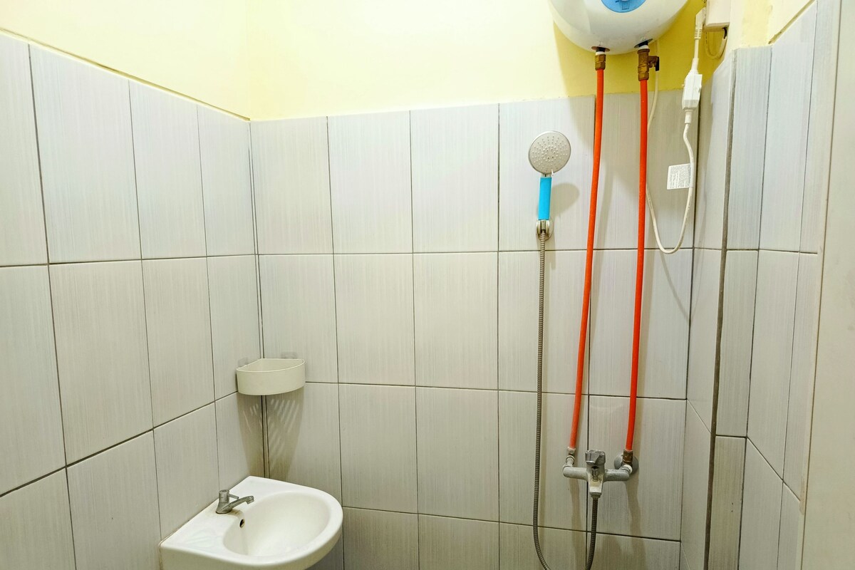 A bathroom with a sink, a shower with a handheld showerhead, and a toilet.