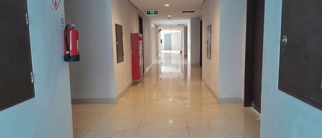 A hallway with a fire extinguisher, a red cabinet, and an exit sign.