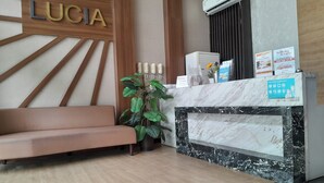A reception area with a marble counter, a sofa, and a wall-mounted sign reading "LUCIA".