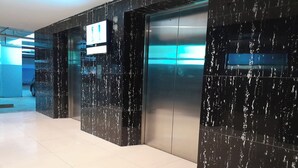 A modern elevator with a digital display and a car parked outside.