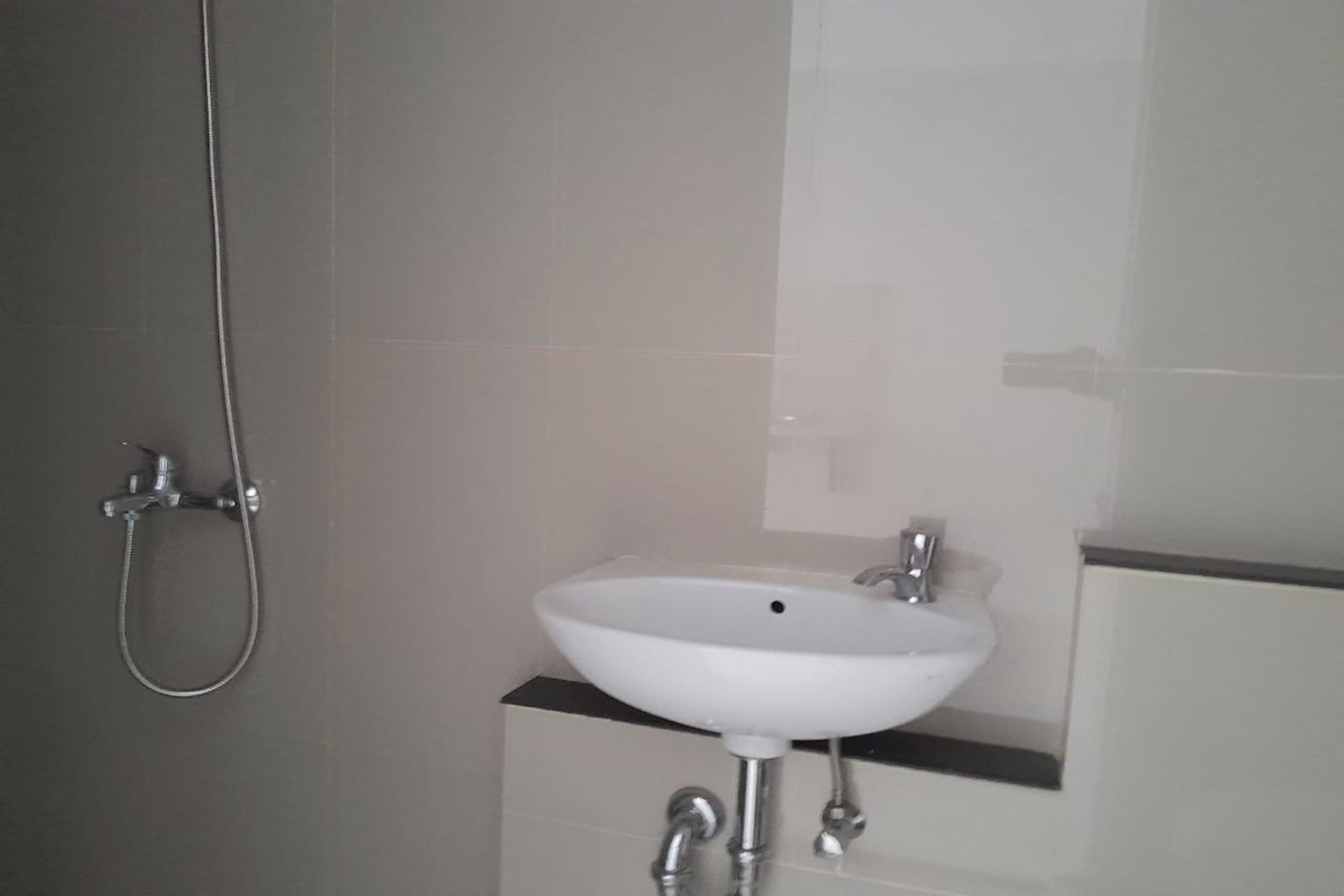 A bathroom with a white sink, a shower, and a mirror.