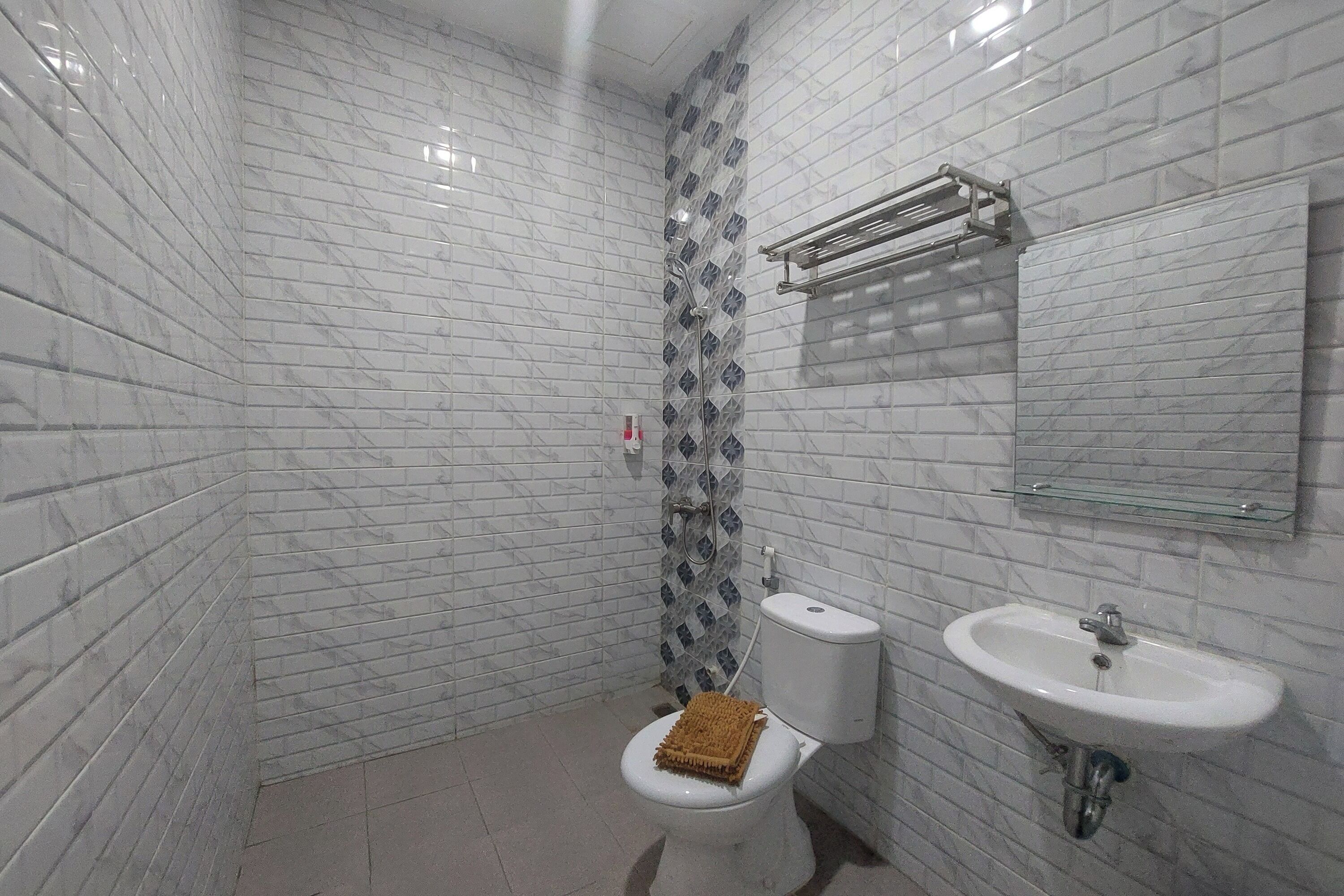 A bathroom with white marble tiles, a toilet, a sink, and a shower area.
