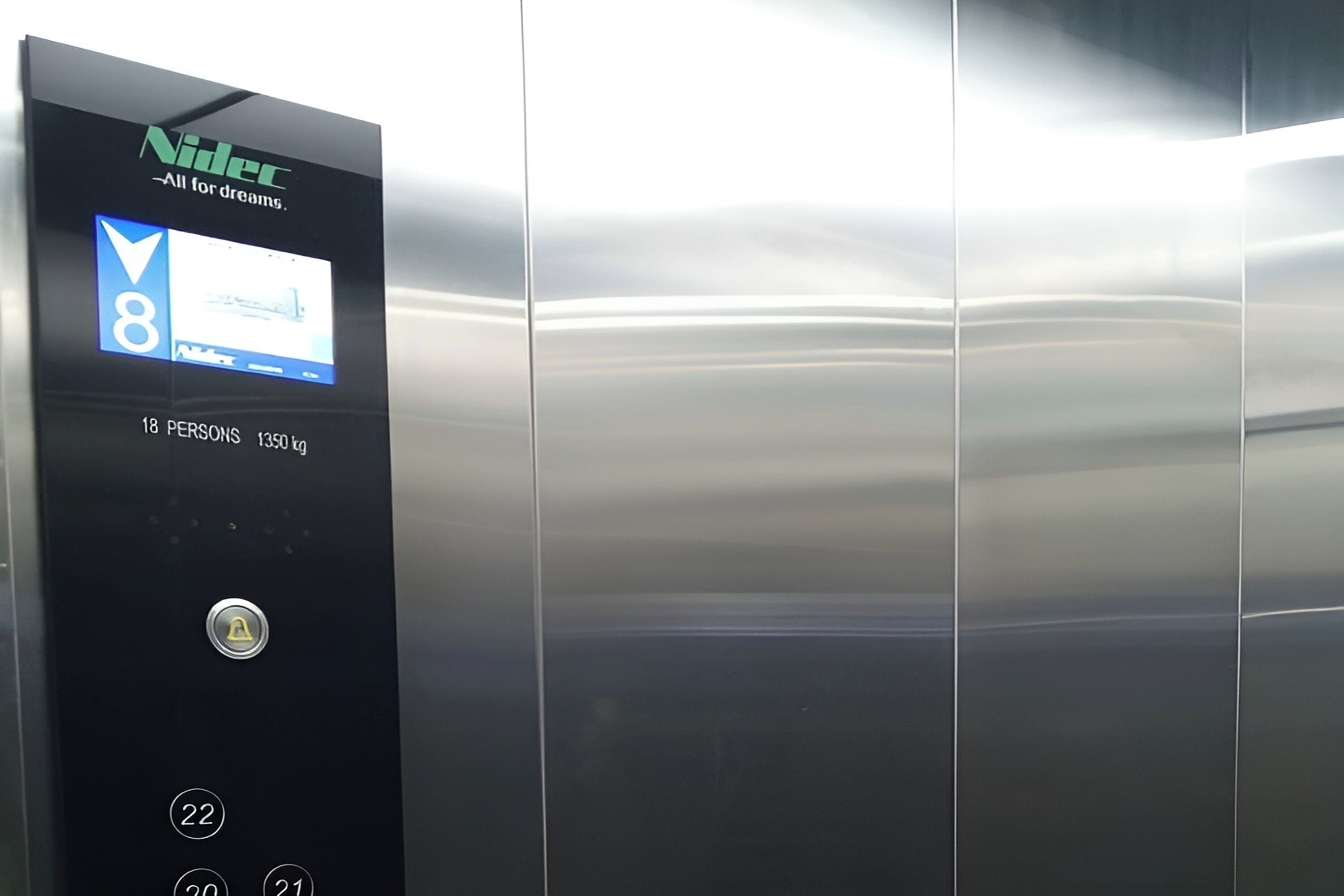 An elevator control panel with a digital display, a weight limit sign, and floor selection buttons.