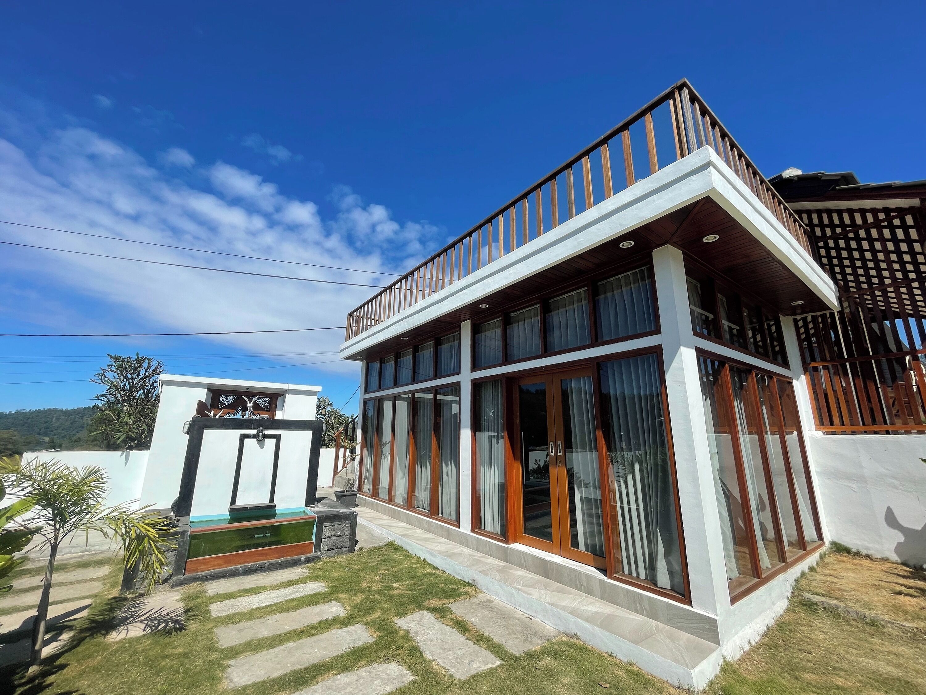 A modern two-story house with large windows, a balcony, and a well-maintained lawn.