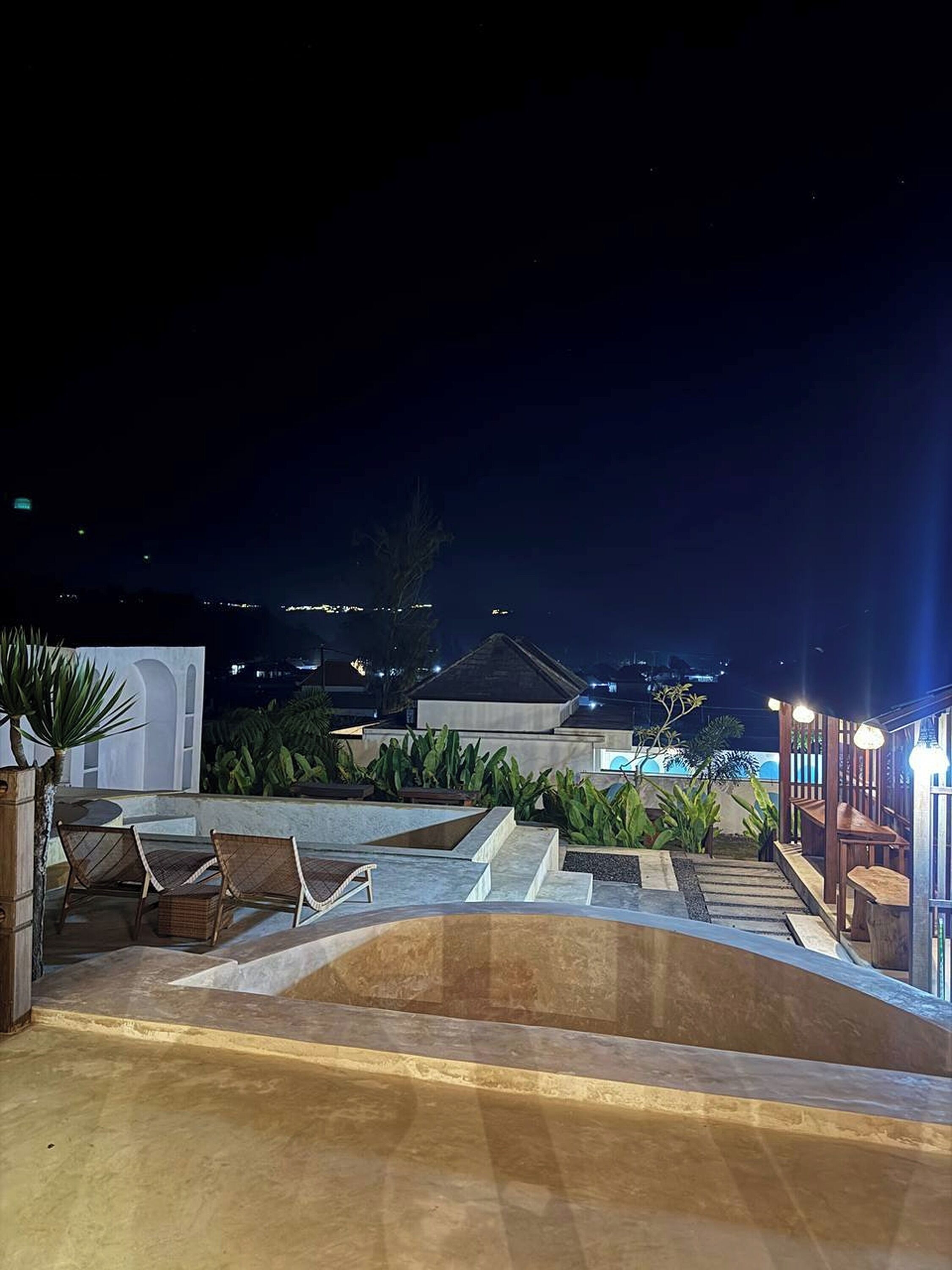 Un espace piscine aménagé sur le toit, avec des sièges et des marches menant à une terrasse.