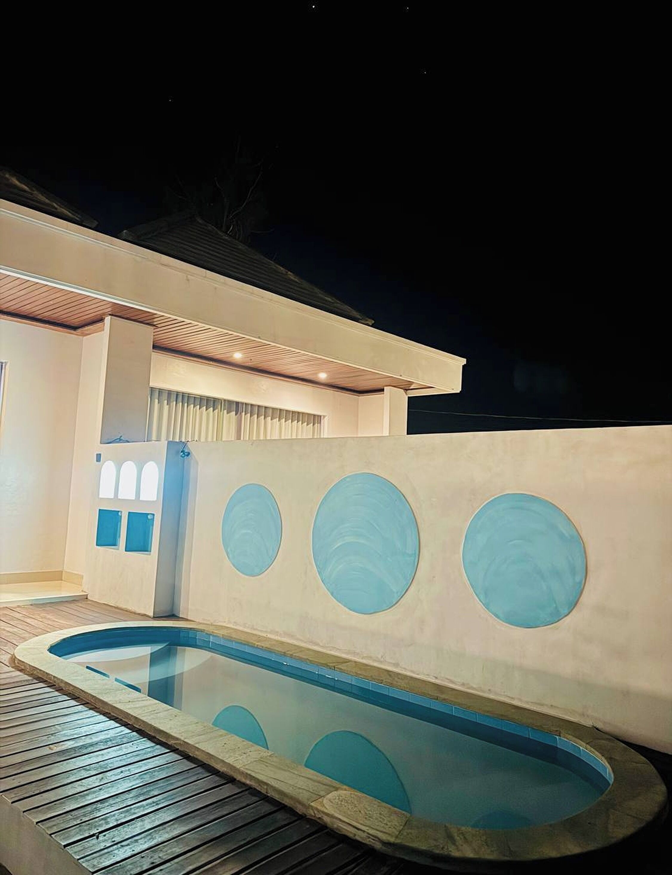 A modern house with a swimming pool, a covered patio, and a large window.
