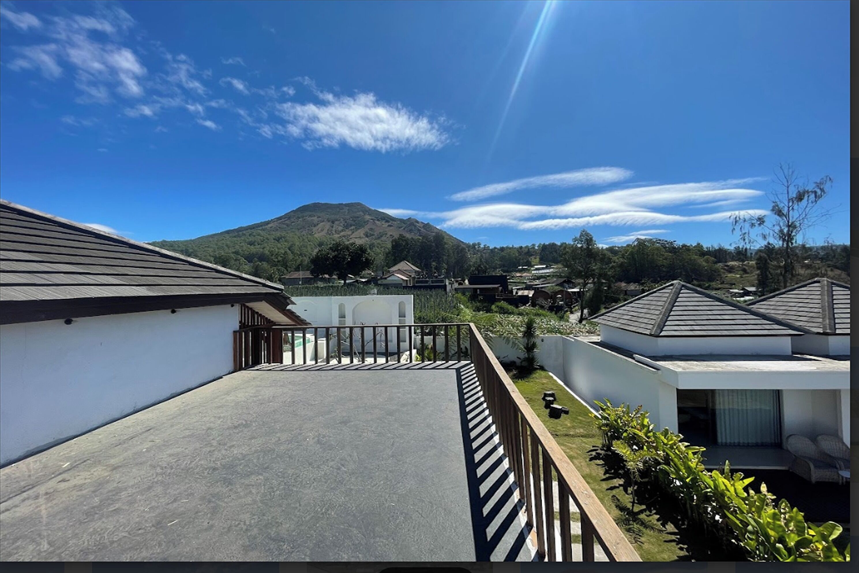 Un quartiere residenziale con case moderne, cielo sereno e una montagna sullo sfondo.
