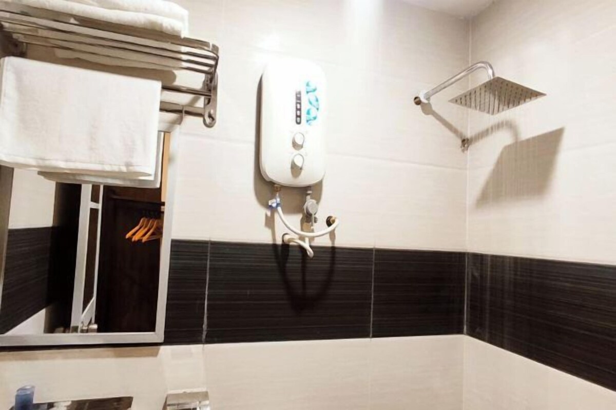 A bathroom with a towel rack, a handheld showerhead, and a mirror.