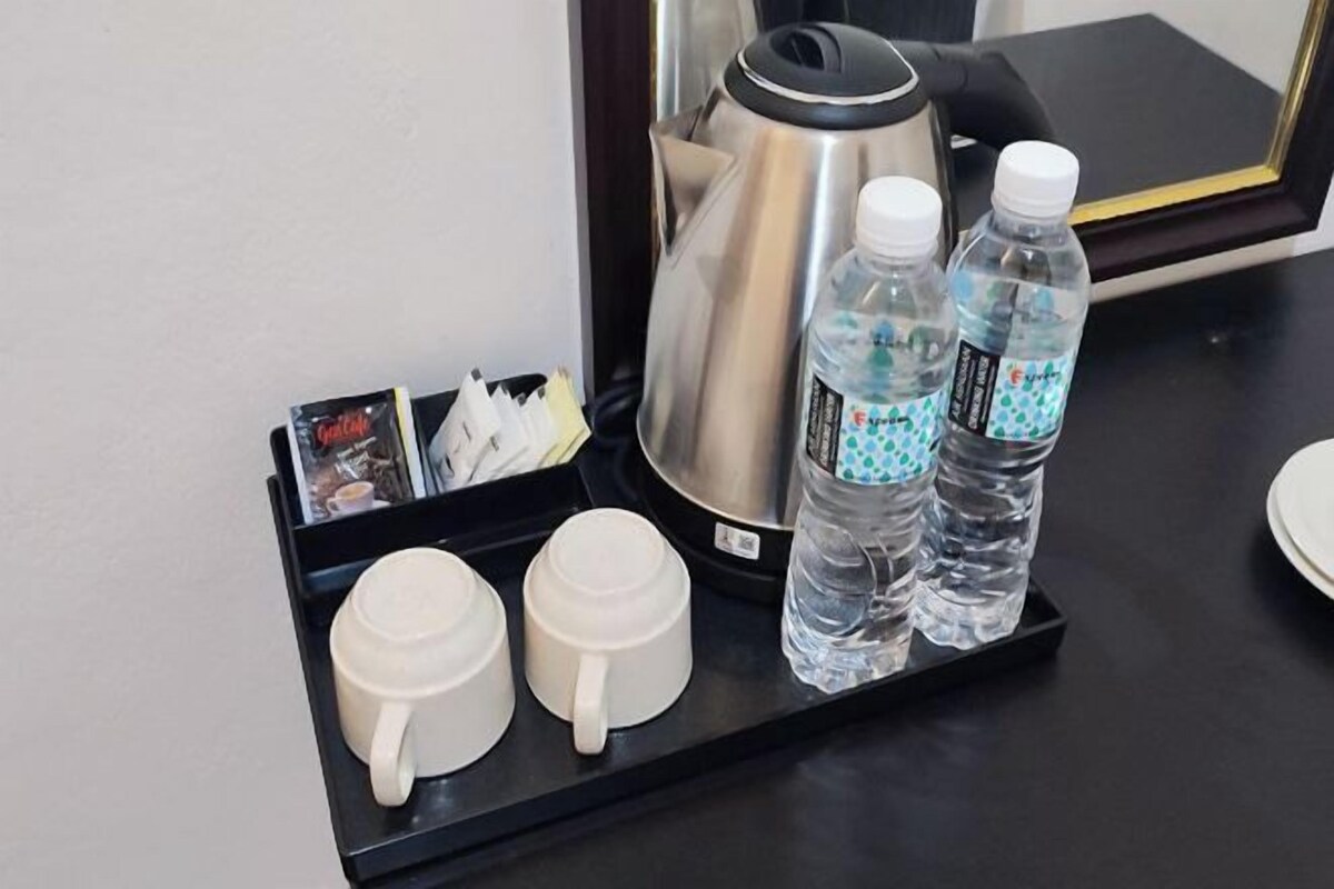 A coffee station with a coffee pot, two cups, and two water bottles on a tray.
