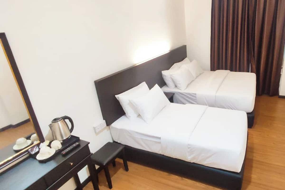 A hotel room with two beds, a desk with a coffee maker, and a mirror.