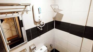 A bathroom with a toilet, a hand dryer, a towel rack, and a shower area.