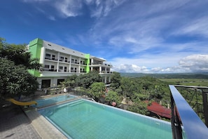 A hotel with a pool, green and white exterior, and a view of the landscape. - Amazing View Mountain Farm Resort (Mabitac)