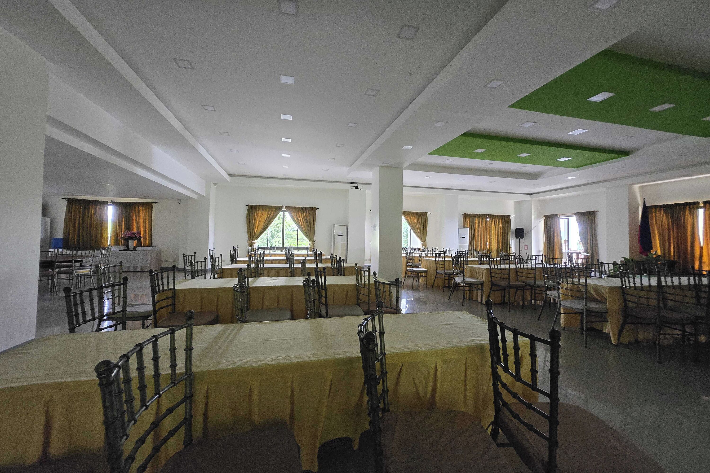 A large hall with multiple tables and chairs, arranged in rows.