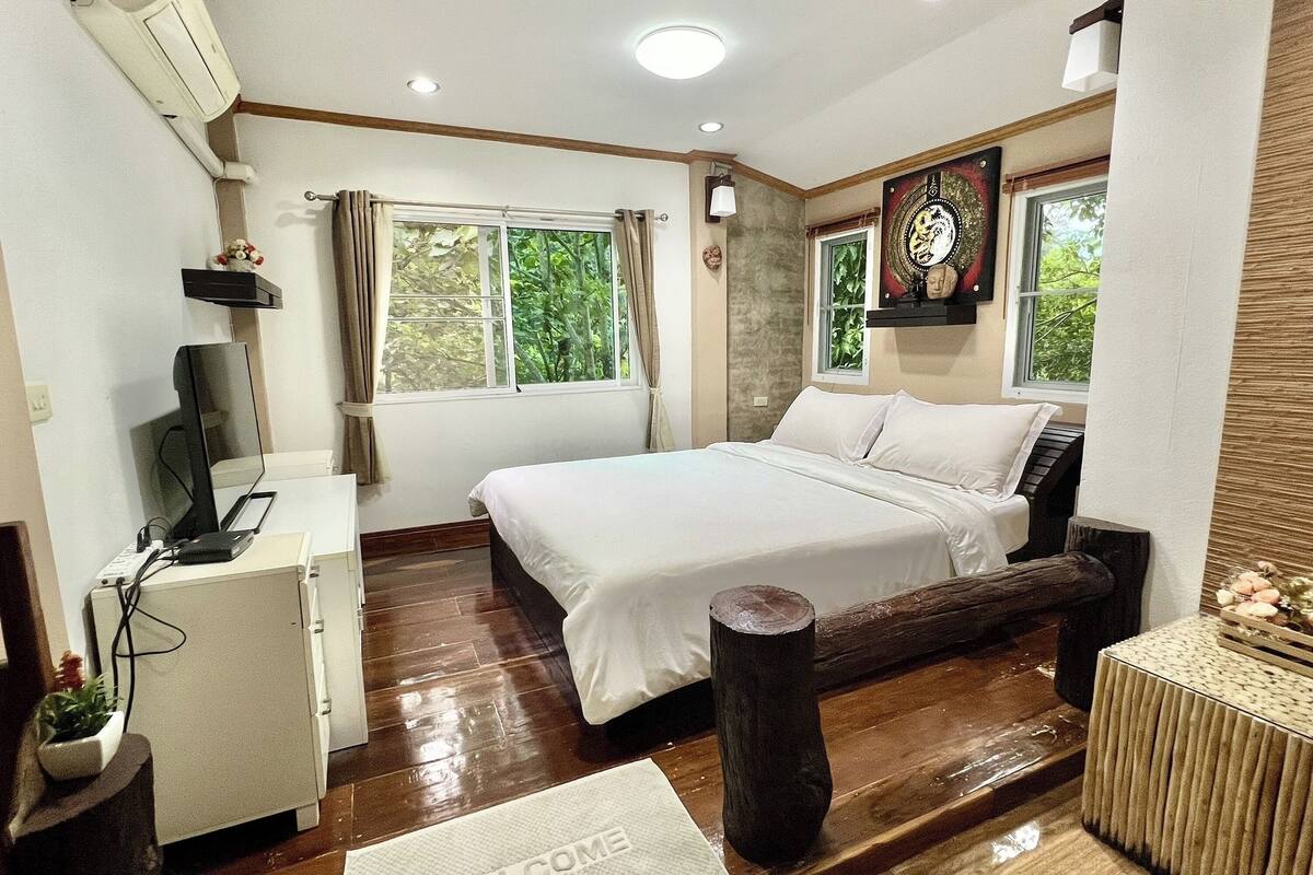 A bedroom with a bed, a desk, and a window.