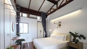 A bedroom with a bed, bedside table, nightstand, and a wall-mounted deer decoration.