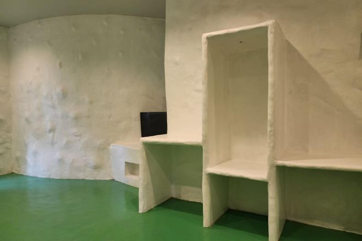 A room with a green floor, white walls, and a white chair.
