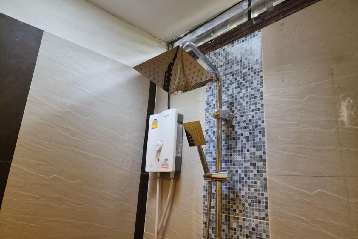 Ein Duschbereich mit gefliesten Wänden, einer Duschbrause und einem Warmwasserbereiter.