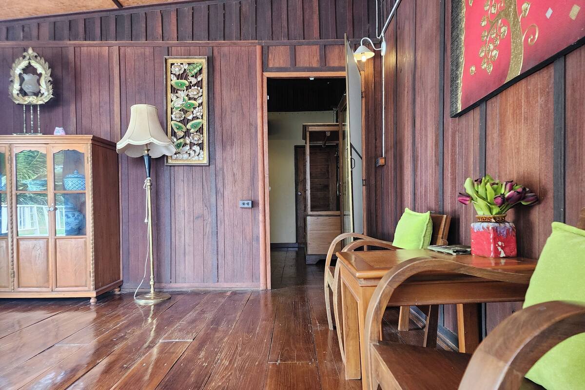 Une pièce aux murs lambrés, avec un meuble en bois, un lampadaire et une table à manger entourée de chaises.