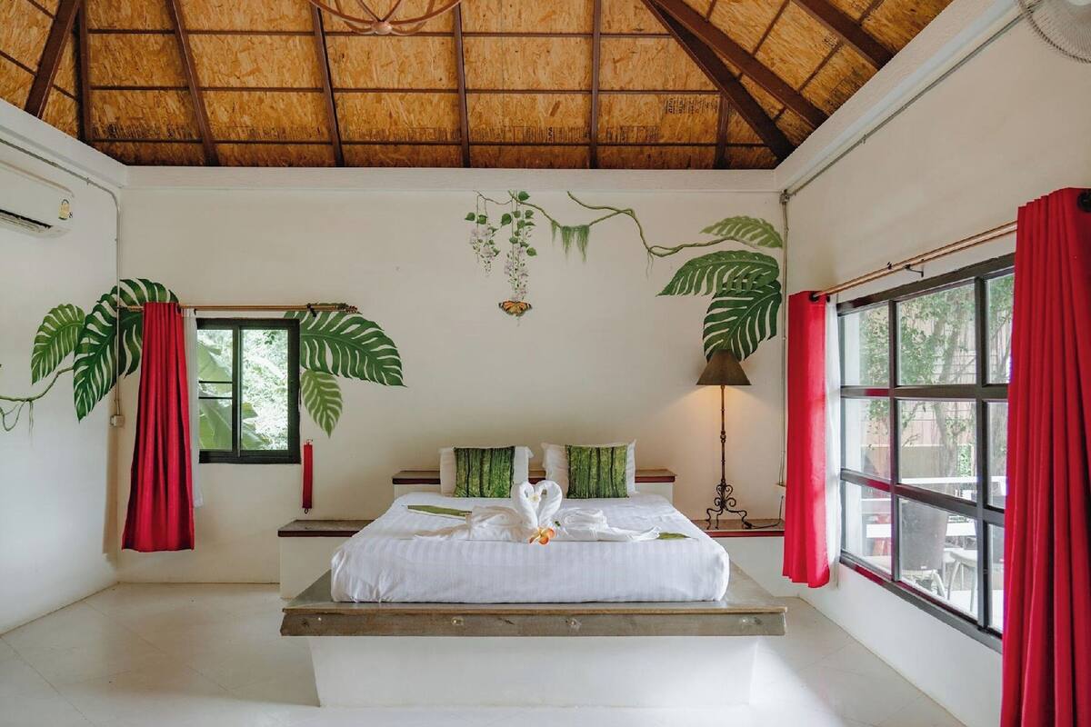 Une pièce avec un lit, une fenêtre et un ventilateur de plafond.
