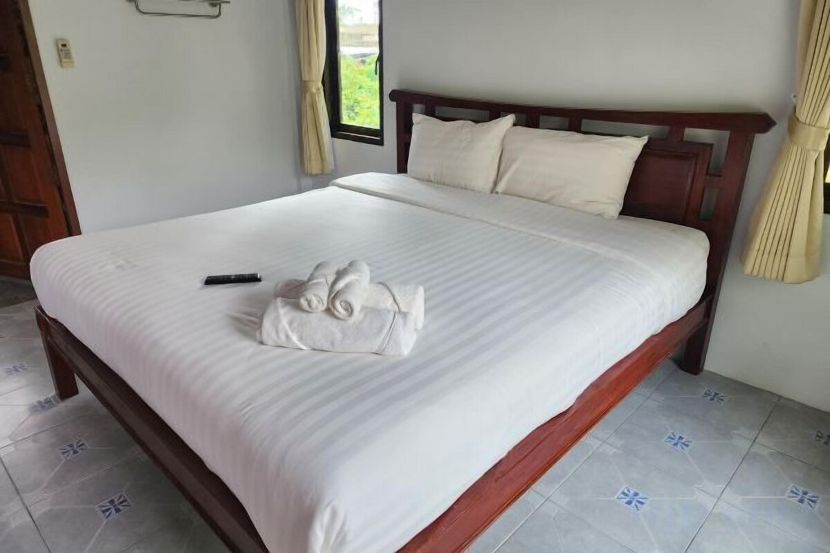 A neatly made bed with a remote control and a towel on the bed.